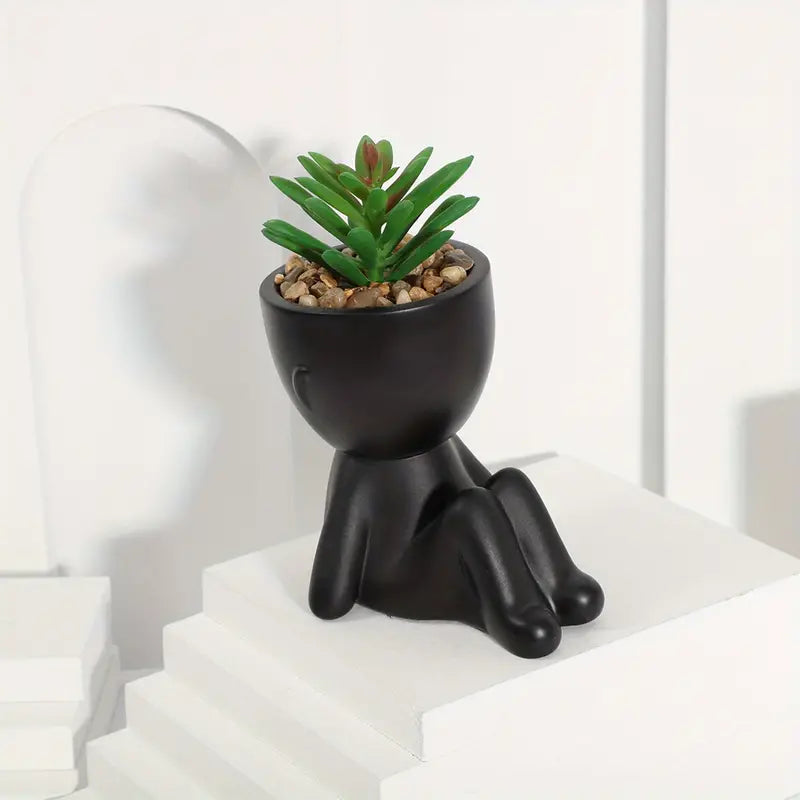 piantine artificiali, vasi a forma di omino, piantine in vaso, piantine finte, decorazioni originali, piantine arredamento casa, piantine in vaso plastica nera, piantine posizioni diverse, piantine moderne, piante decorative senza manutenzione.